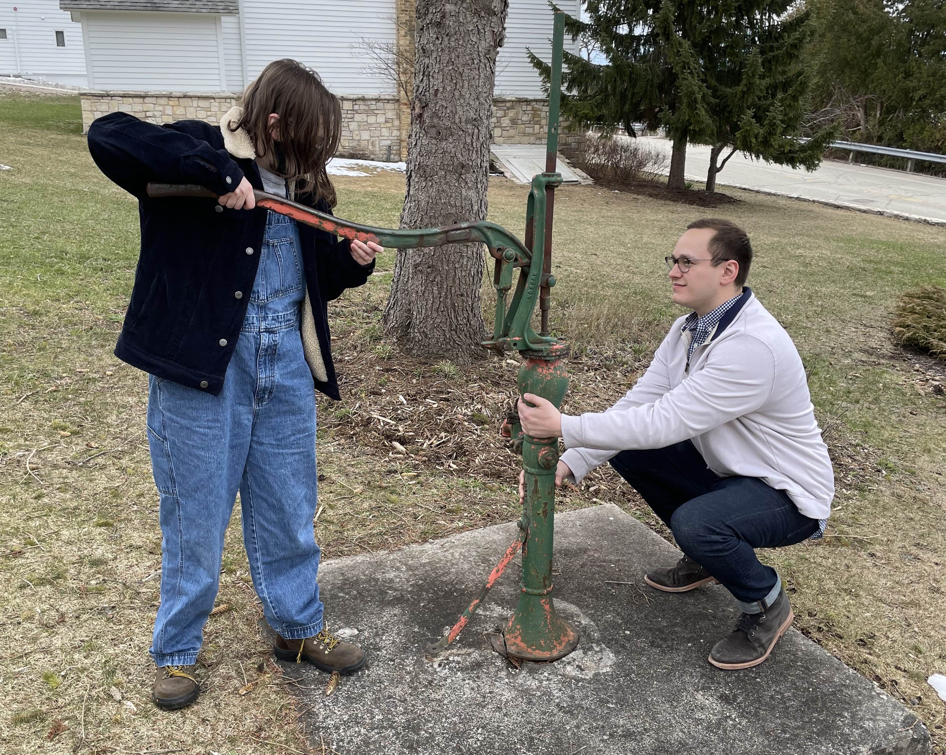 Two students working a water pump